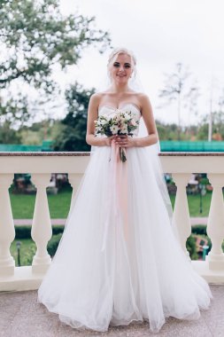 Gelinlik içindeki genç gelin elinde güzel bir buket çiçek tutuyor.                  