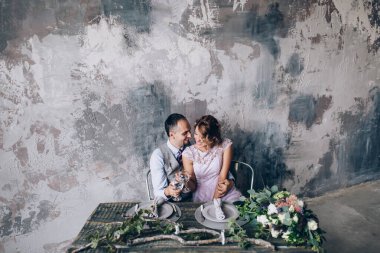 Duvarın arkasında poz veren mutlu gelin ve damat 