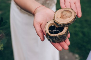 Gelin avucunda alyansları olan tahta kutu.