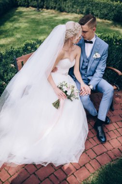 Gelin ve damat düğün günü parkta bankta oturuyorlar. 