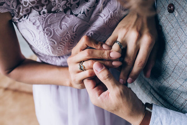 close-up view of young wedding couple holding hands and wearing rings