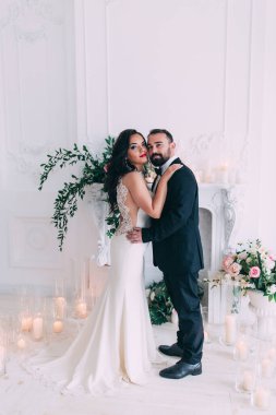 Güzel, mutlu, genç gelin ve damat düğün iç mekanında poz veriyor..       