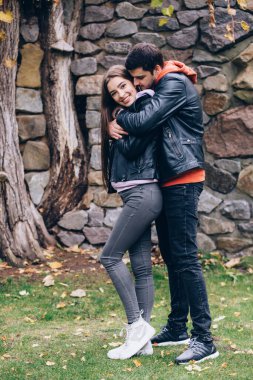 Taş duvarın yanında birbirine sarılan genç bir çiftin portresi. Aşk hikayesi..