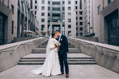 Güzel, mutlu genç gelin ve damat eski kasabanın arka planında öpüşüyorlar..