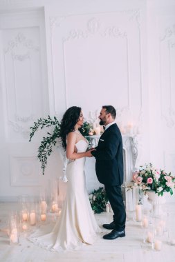 Güzel, mutlu, genç gelin ve damat düğün iç mekanında poz veriyor..       