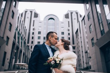 Güzel, mutlu genç gelin ve damat eski kasabanın arka planında öpüşüyorlar..