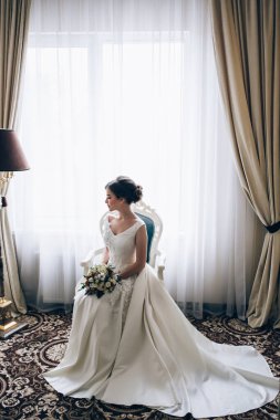 Beyaz elbiseli güzel, genç gelin zarif iç çamaşırlarıyla poz veriyor.       