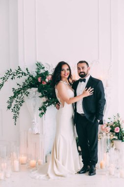 Güzel, mutlu, genç gelin ve damat düğün iç mekanında poz veriyor..       