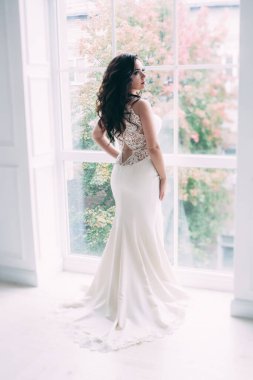 Gelinin arka görünüşü zarif bir şekilde pencerenin yanında duruyor