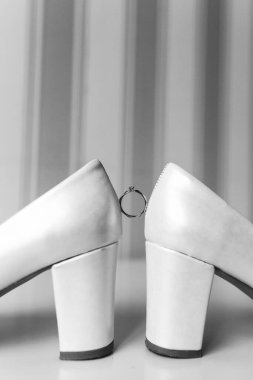 Topuklu ayakkabılar arasındaki nikah yüzüğünün yakın görüntüsü. 