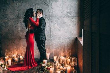 Şatafatlı bir iç mekanda mumları olan zarif genç bir çift.              