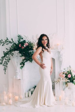 Beyaz elbiseli güzel, genç gelin zarif iç çamaşırlarıyla poz veriyor.       