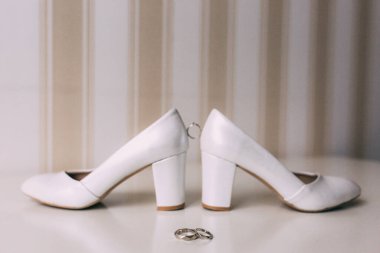 Topuklu ayakkabılar arasındaki nikah yüzüğünün yakın görüntüsü. 