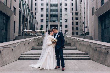 Güzel, mutlu genç gelin ve damat eski kasabanın arka planında öpüşüyorlar..