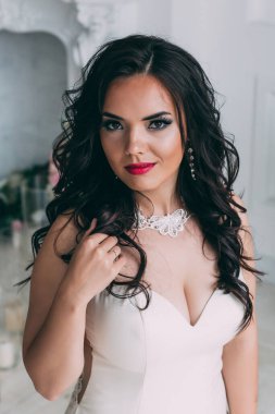 Beyaz elbiseli güzel, genç gelin zarif iç çamaşırlarıyla poz veriyor.       