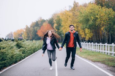Şehir parkında, asfalt yolda koşan romantik bir çiftin portresi.