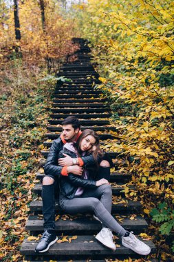 Sonbahar parkında merdivenlerde birbirine aşık güzel bir çift oturuyor.              