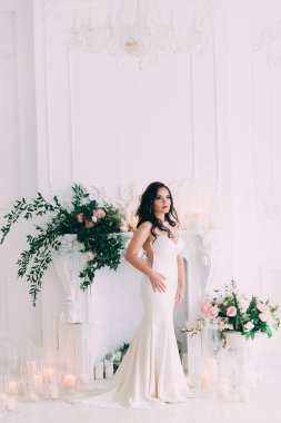 Beyaz elbiseli güzel, genç gelin zarif iç çamaşırlarıyla poz veriyor.       