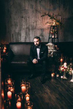 Damat düğün süslemeli stüdyoda poz veriyor.