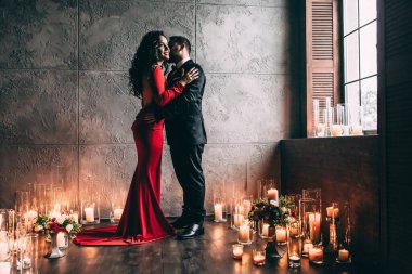 Şatafatlı bir iç mekanda mumları olan zarif genç bir çift.              