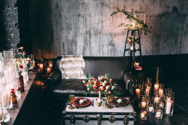 Deri kanepe ve servis masası, çiçekler ve mumlarla süslenmiş.