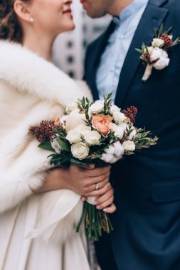 Güzel bir düğün çifti ellerinde buket ve şehirde birlikte poz veriyorlar.