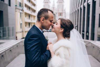 Güzel, mutlu genç gelin ve damat eski kasabanın arka planında öpüşüyorlar..