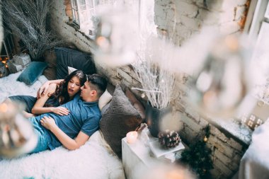 Yüksek açılı bir bakış açısıyla birbirine aşık genç çiftin rahat bir şekilde yatağında uzanması.          