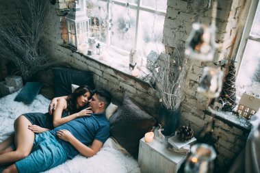 Yüksek açılı bir bakış açısıyla birbirine aşık genç çiftin rahat bir şekilde yatağında uzanması.          