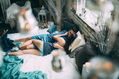 Yüksek açılı bir bakış açısıyla birbirine aşık genç çiftin rahat bir şekilde yatağında uzanması.          