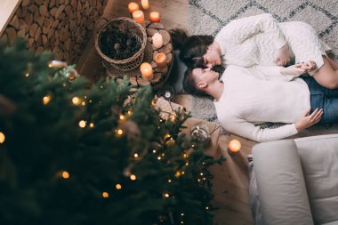 Genç ve aşık bir çiftin Noel ağacının yanında yerde yatışının en üst görüntüsü.