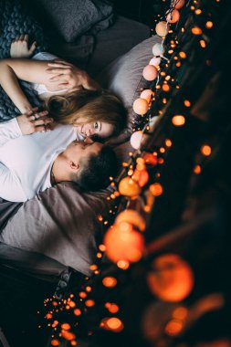 Genç çift yatakta uzanıyor ve sıcak yatak odasında sarılıyorlar. 