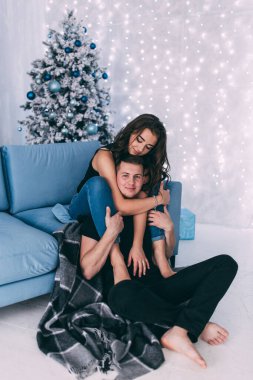 Genç bir çift, Noel süslemeleriyle dolu rahat bir stüdyoda poz veriyor. Yeni yılın aşk hikayesi..