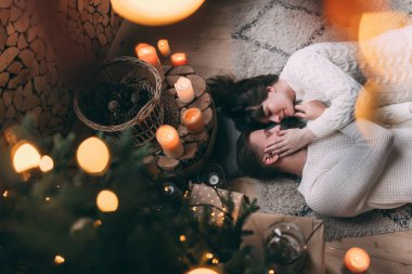 Genç ve aşık bir çiftin Noel ağacının yanında yerde yatışının en üst görüntüsü.