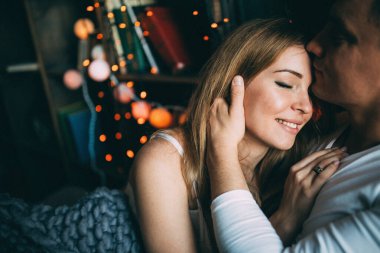 Genç çift yatakta uzanıyor ve sıcak yatak odasında sarılıyorlar. 