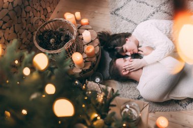 Genç ve aşık bir çiftin Noel ağacının yanında yerde yatışının en üst görüntüsü.