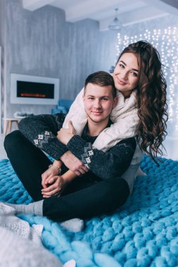 Genç bir çift, Noel süslemeleriyle dolu rahat bir stüdyoda yatakta poz veriyor. Yeni yılın aşk hikayesi..