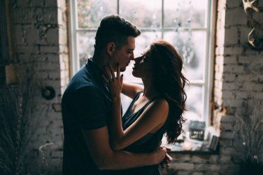 Mutlu genç adam ve kadın samimi bir odada sarılıp öpüşüyor..                