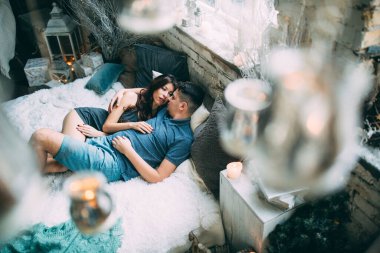 Yüksek açılı bir bakış açısıyla birbirine aşık genç çiftin rahat bir şekilde yatağında uzanması.          