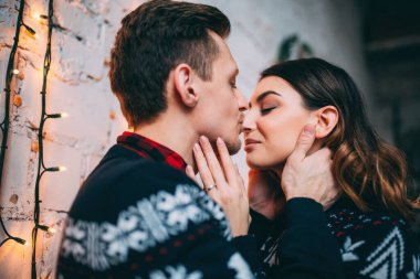 Stüdyoda Noel dekoruyla poz veren mutlu çifti kapatın. Geyik ve benzer kazaklar giyin. 