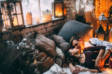 Güzel, genç ve aşık bir çift, rahat bir odada, yatakta yatıyor.         