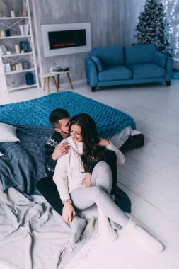 Genç ve güzel bir çift Noel 'de evde birbirlerine sarılıyorlar.                      