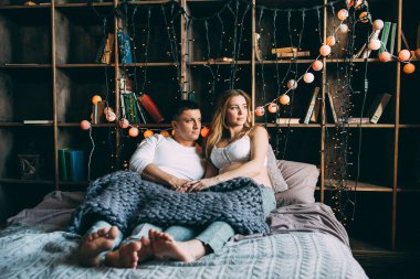 Genç çift yatakta uzanıyor ve sıcak yatak odasında sarılıyorlar. 