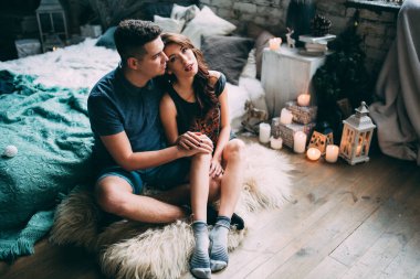 Güzel, genç bir çift yatak odasında oturuyor. 