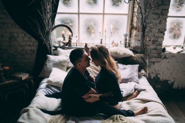 Genç ve güzel bir çift romantik bir evde, yatakta mutlu bir anın tadını çıkarıyor..