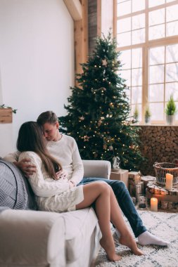 Genç ve aşık bir çift, Noel süsleriyle süslenmiş rahat bir stüdyoda poz veriyor. Yeni yılın aşk hikayesi..