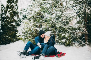 Birbirine aşık genç çift köknar ağacına poz veren kışlık kıyafetler giyiyor. Yeni yılın aşk hikayesi.. 