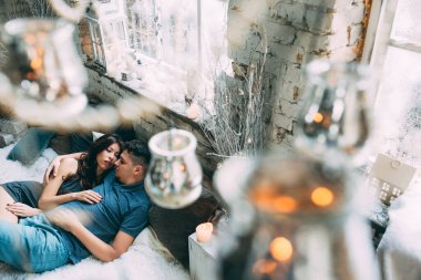 Yüksek açılı bir bakış açısıyla birbirine aşık genç çiftin rahat bir şekilde yatağında uzanması.          