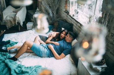 Yüksek açılı bir bakış açısıyla birbirine aşık genç çiftin rahat bir şekilde yatağında uzanması.          