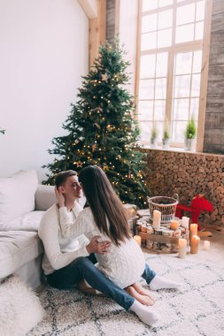 Kocasıyla birlikte Noel süslemeli stüdyoda güzel ve genç bir hamile kadın. 